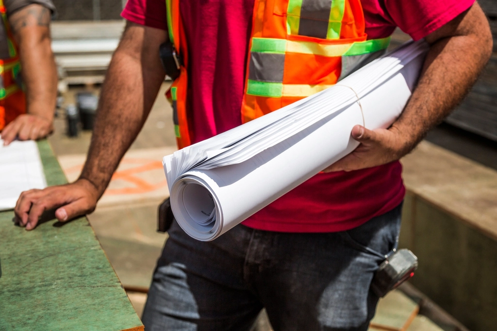 construction worked hold roll blueprints